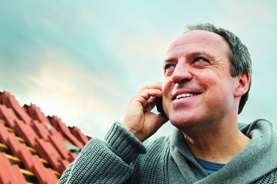 Contractor on phone in front of roof